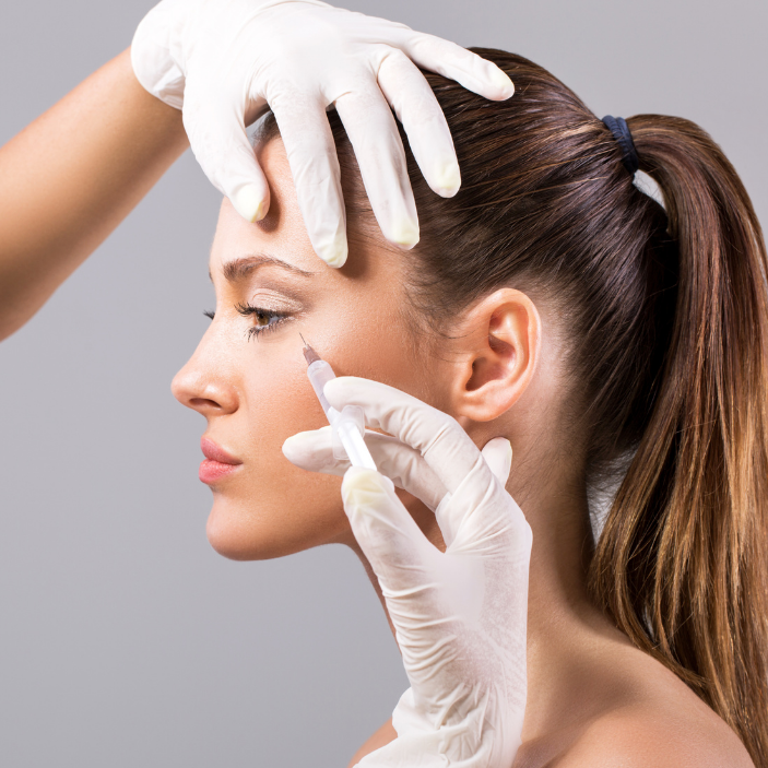 Woman receiving cosmetic injection with gloved hands on a gray background