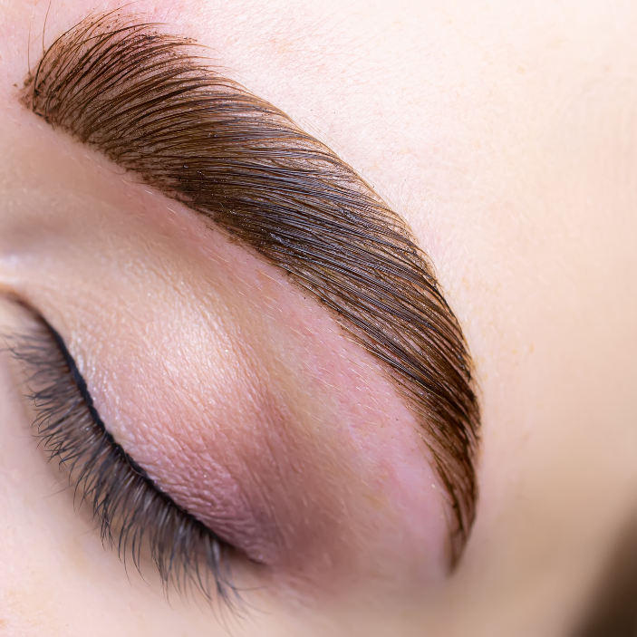 Close-up of an eye with a well-groomed eyebrow and pink eyeshadow.